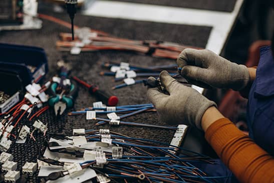 A worker assembling electrical components for a wiring harness